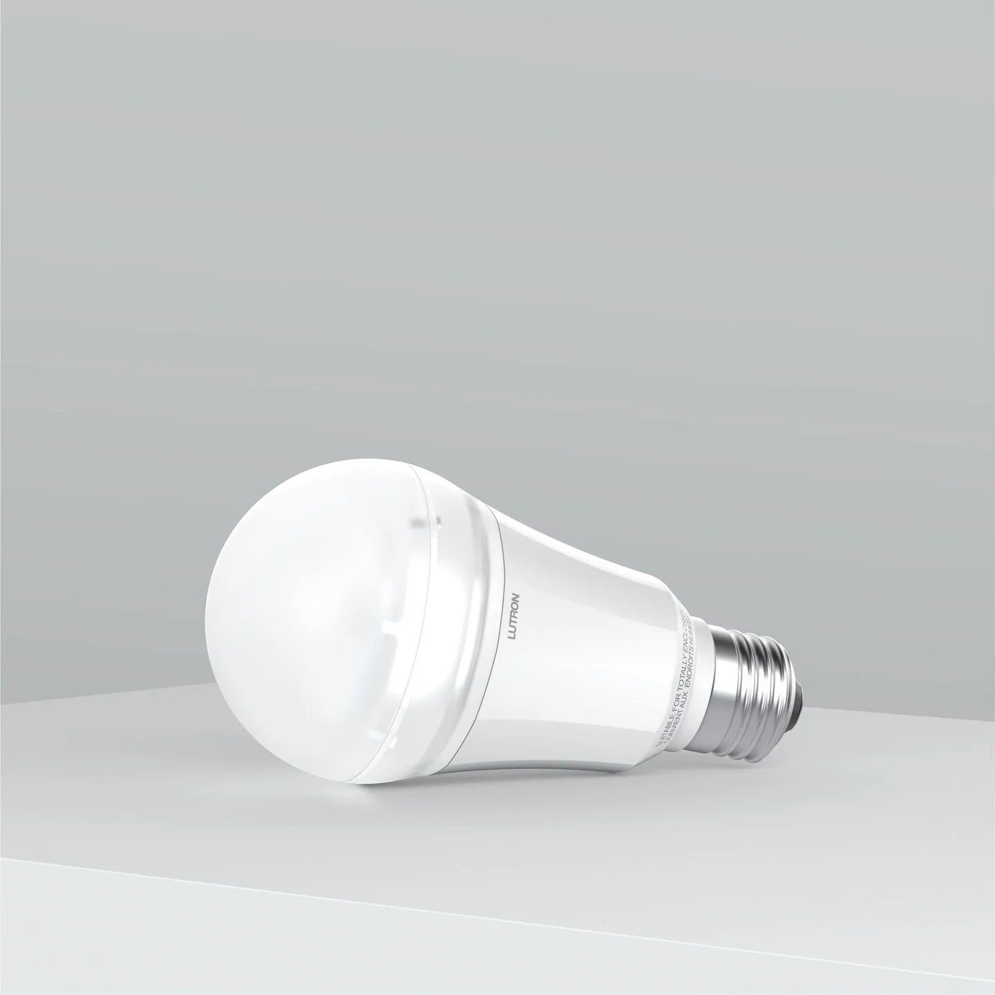 White LED light bulb lying on its side on a gray surface, with branding visible on the bulb.