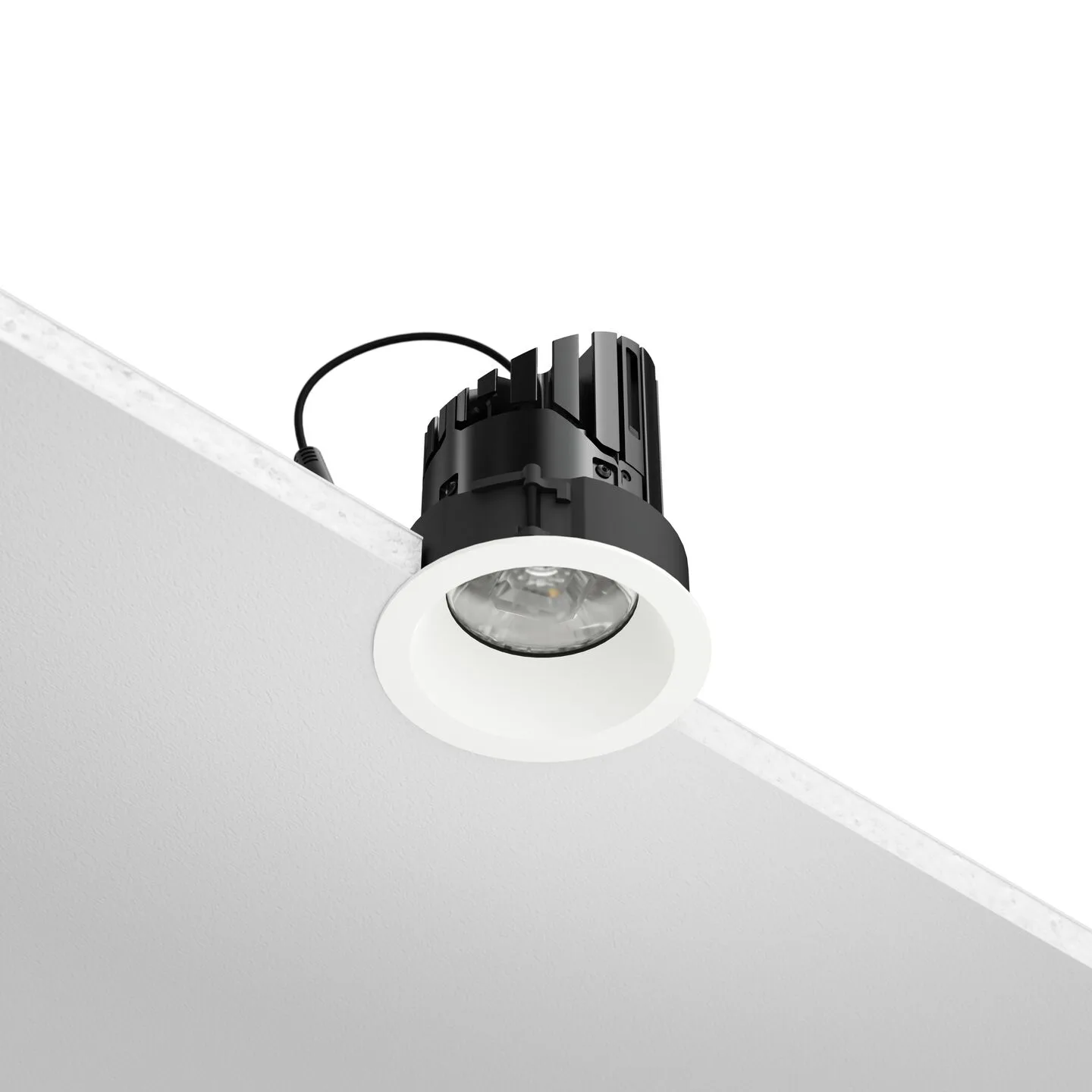 Black recessed spotlight with a white trim mounted on a white ceiling near a wall corner.