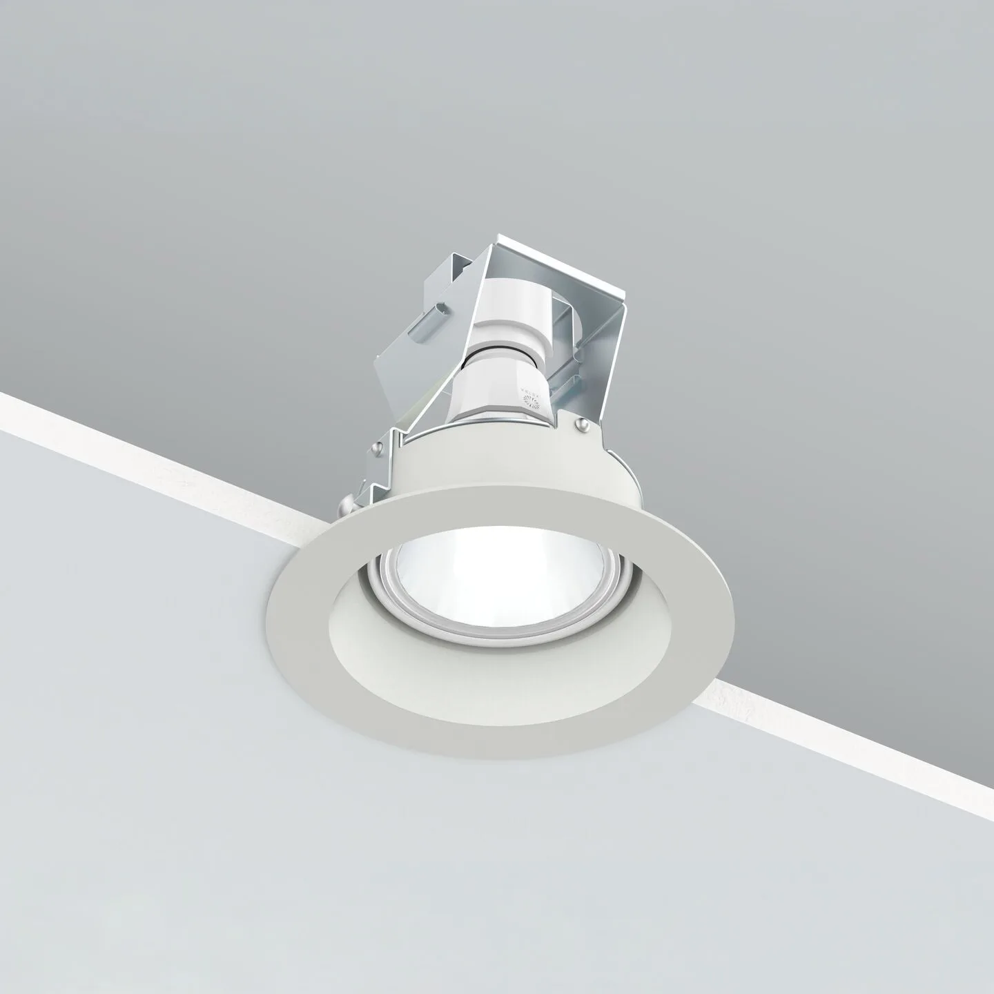 White recessed ceiling downlight with circular trim mounted on a gray ceiling surface, angled to illuminate downward