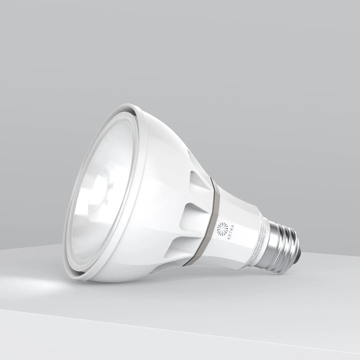White LED spotlight bulb lying on a light gray surface against a gray gradient background, angled to the left.