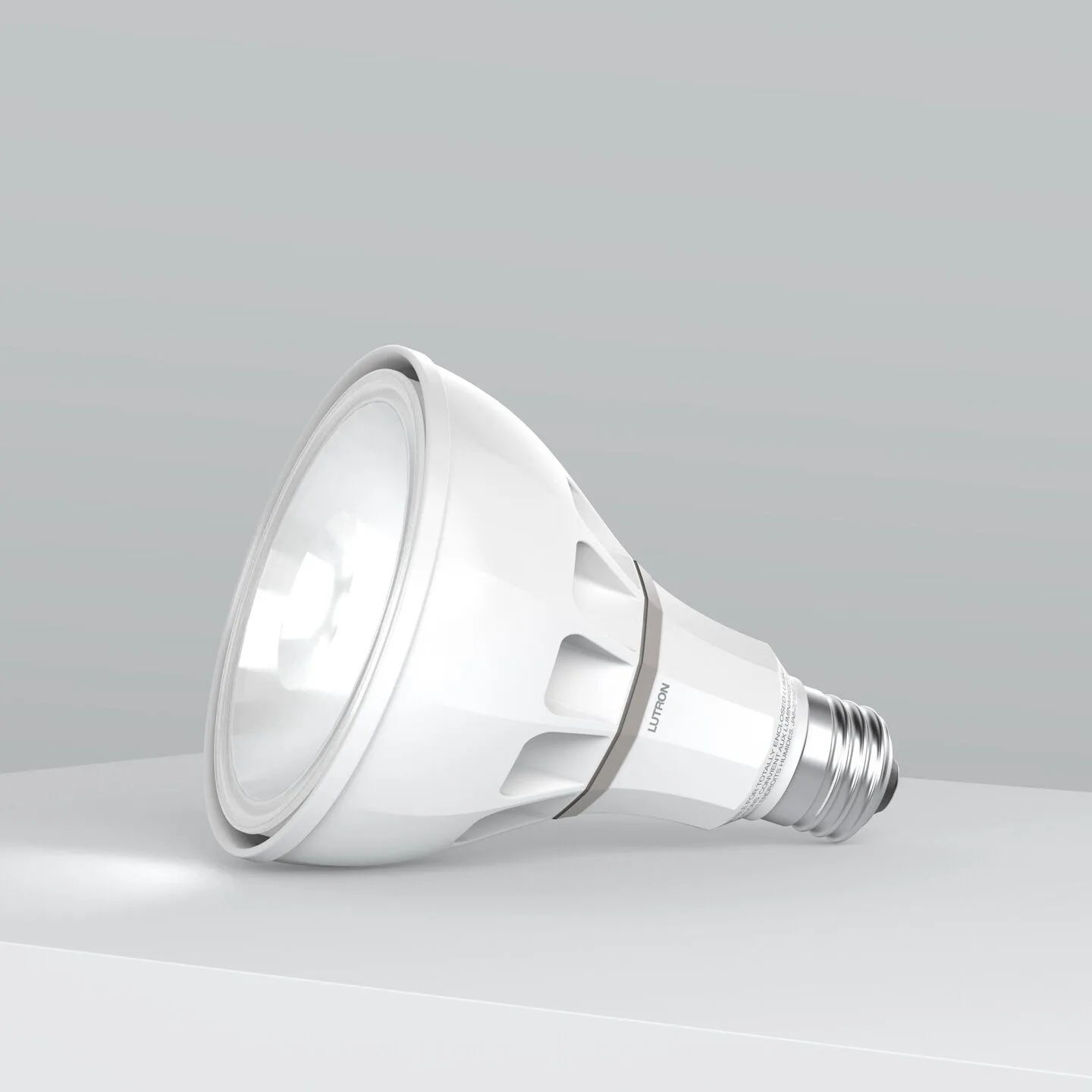 White LED light bulb lying on its side on a light gray surface with a soft gray gradient background.