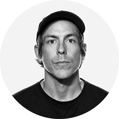 BLADLEY Portrait of a man wearing a black baseball cap and black shirt, looking at the camera.
