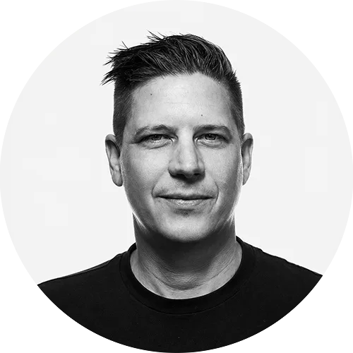 CHEYNE Portrait of a man with short dark hair wearing a black shirt, facing the camera with a neutral expression.