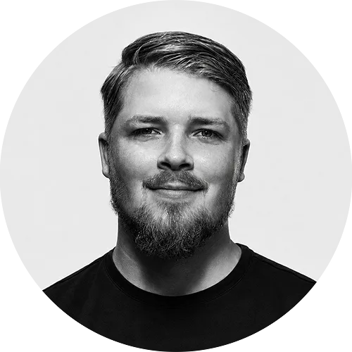 HARLEY Portrait of a man with short hair and a trimmed beard, wearing a black shirt and a subtle smile.