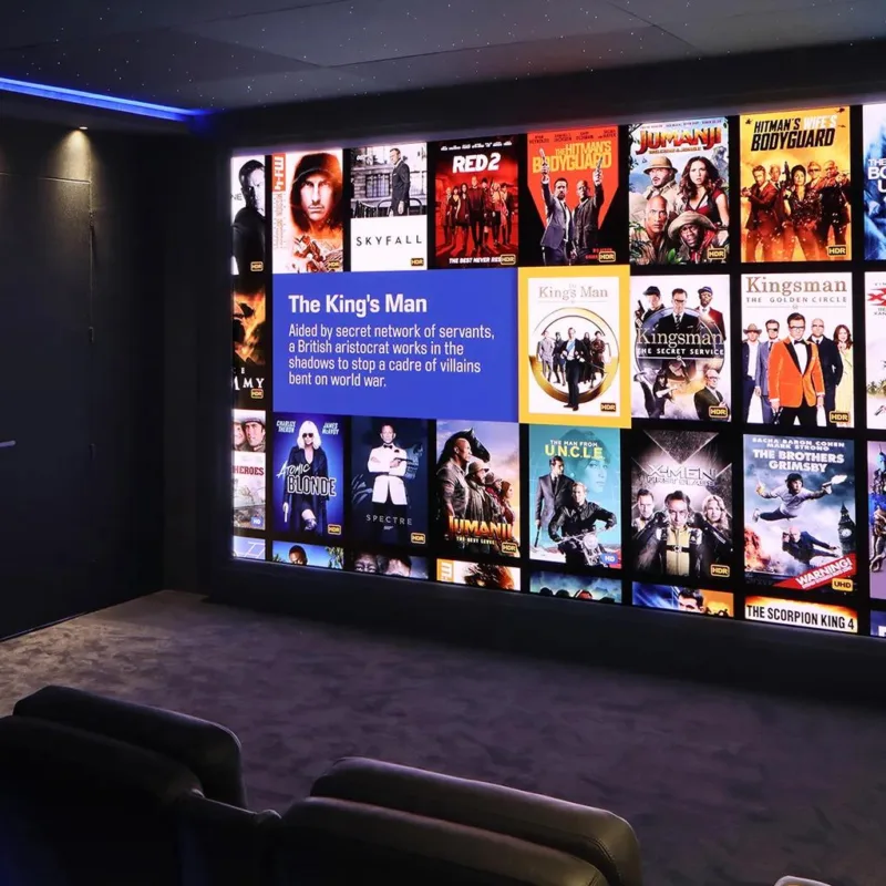 Barco residential home cinema with reclining seats and a wall display showing a film library